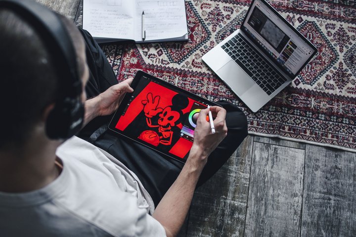 Designer working on a digital illustration with a tablet and laptop